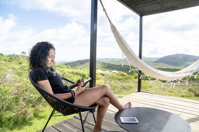 Woman using a digital tablet while relaxing sitting outdoors.