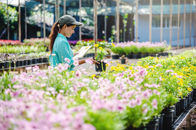 Side view of woman standing in greenhouse