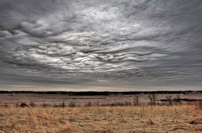 Scenic view of field against storm clouds