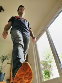 Low angle view of man looking through window at home