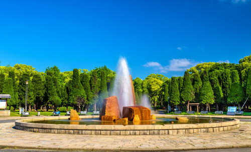Fountain in park against blue sky