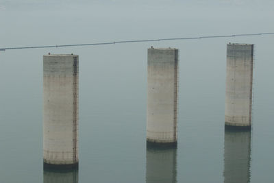 Wooden posts in sea against clear sky