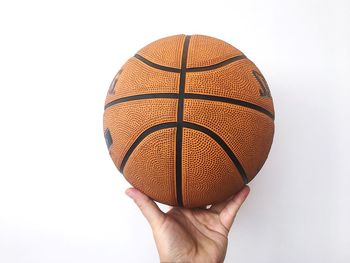 Close-up of hand holding ball against white background