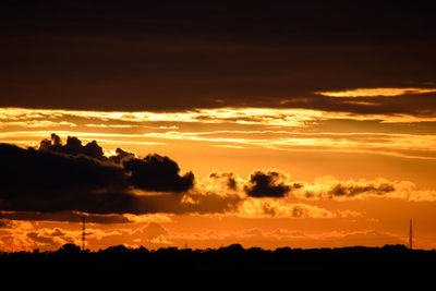 Silhouette landscape against dramatic sky during sunset