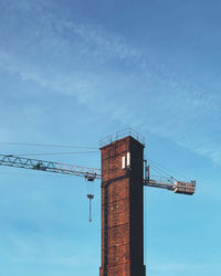 Low angle view of crane at construction site against sky