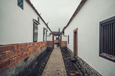 Empty footpath amidst buildings in city