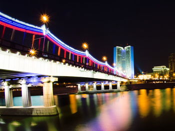 Illuminated bridge over river at night