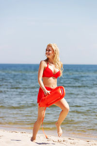 Full length of young woman at beach against sky