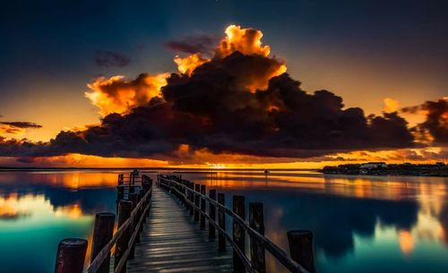 Pier over lake against sky during sunset