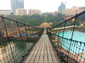 Empty footbridge over sunway lagoon in city