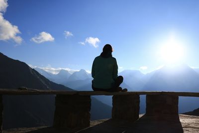 Rear view of woman sitting on bench at mountain peak