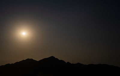 Scenic view of silhouette mountains against clear sky at night