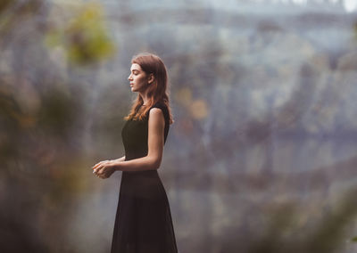 Young woman standing against sky