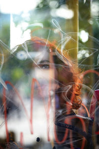 Close-up of young woman against window