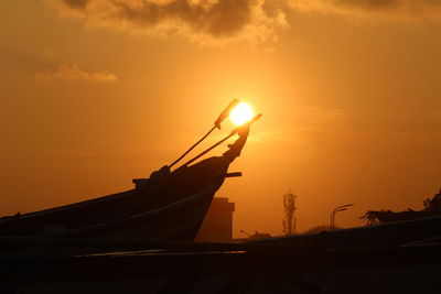 Silhouette boat moored in sea against orange sky. sunset between the boat captured on perfect timing