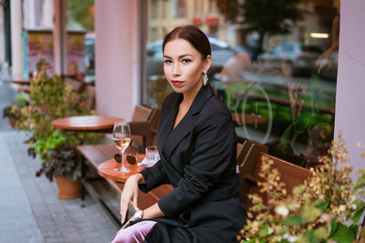 Beautiful woman sits in a street cafe with a glass of wine person