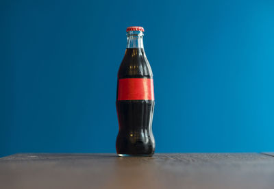 Close-up of glass bottle on table against blue background