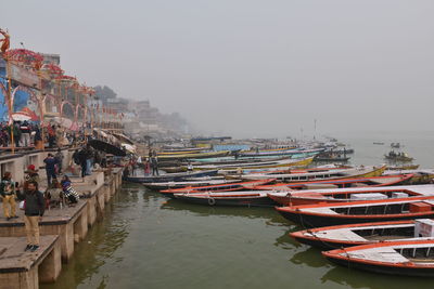 Boats moored at harbor against sky