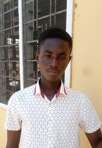 Portrait of young man standing against wall