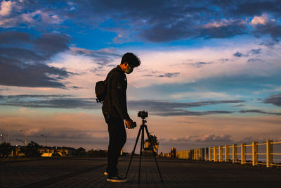 Man photographing against sky during sunset