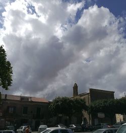Cars on street against cloudy sky