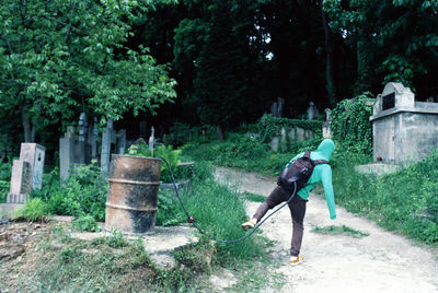 Rear view of man with arms outstretched against plants