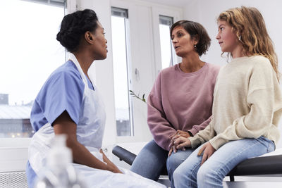 Female doctor talking to girl patient and mother during appointment