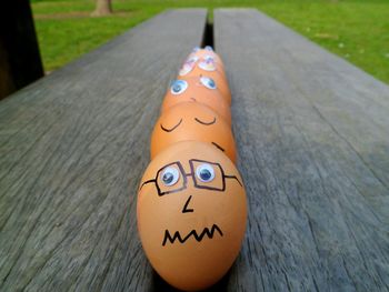 Close-up of face drawn eggs in row on bench