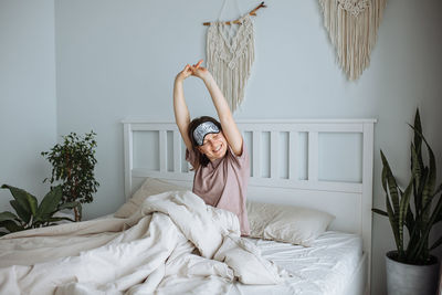 Portrait of young woman sitting on bed at home