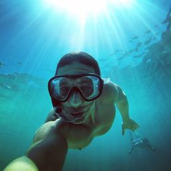 Shirtless man swimming underwater in sea