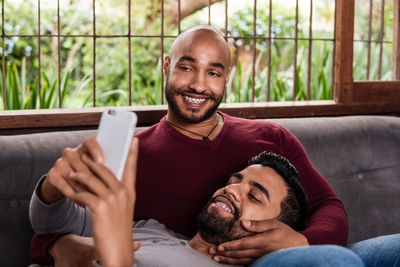 Gay couple looking at mobile phone at home
