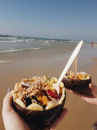 Close-up of hand holding ice cream on beach