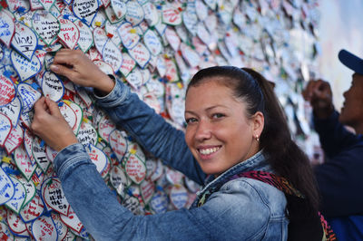 Portrait of smiling woman sticking paper on wall