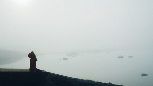 Side view of woman sitting on hill at jokulsarlon lagoon