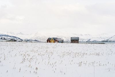 House on snow covered field against sky