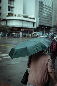 Rear view of people walking on street during rainy season