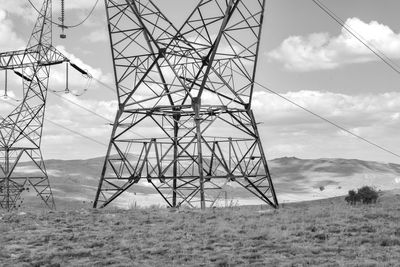 Electricity pylon on field against sky