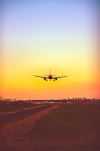 Low angle view of airplane flying against dramatic sky during sunset