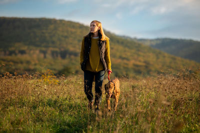 Mature woman walking her beautiful vizsla. dog walking background. woman and dog enjoying walk.