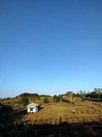 House on field against clear blue sky