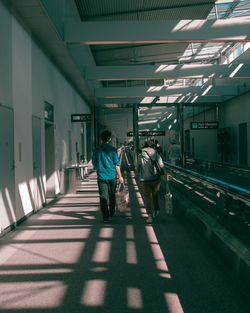 Rear view of people walking in illuminated corridor