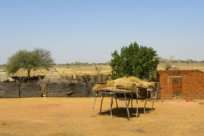 Chairs and table on field against clear sky