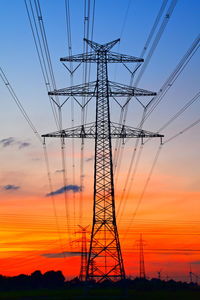 Low angle view of electricity pylon against sky during sunset