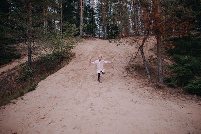 Rear view of woman running on road in forest