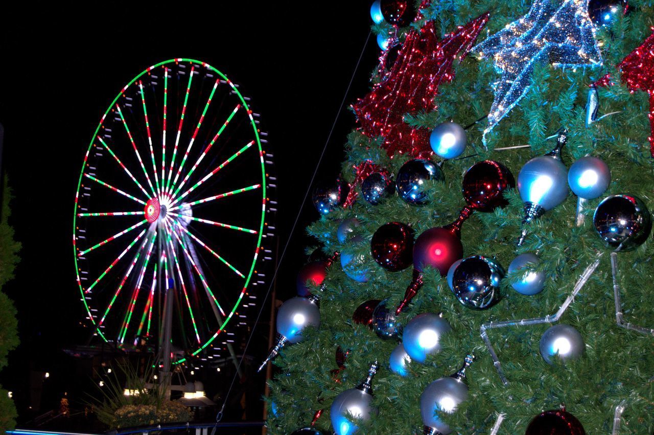 LOW ANGLE VIEW OF ILLUMINATED CHRISTMAS LIGHTS AGAINST SKY AT NIGHT