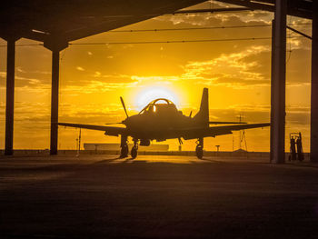 Airplane on runway against sky during sunset