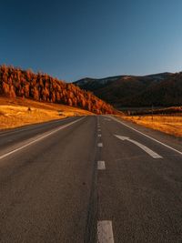 Empty road against clear blue sky