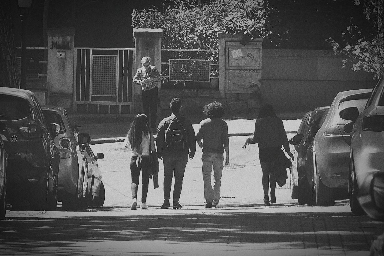 REAR VIEW OF PEOPLE ON ROAD AGAINST CARS