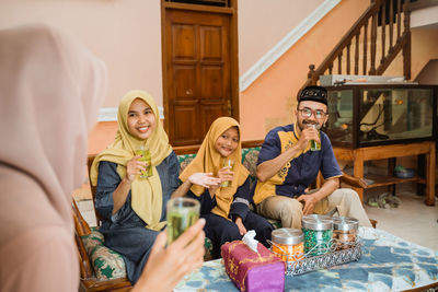 Portrait of smiling friends sitting at home