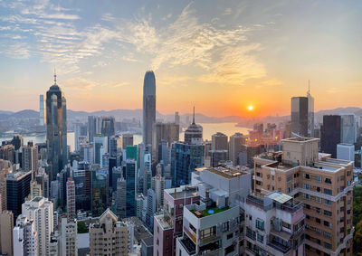 Aerial view of modern buildings in city against sky during sunset